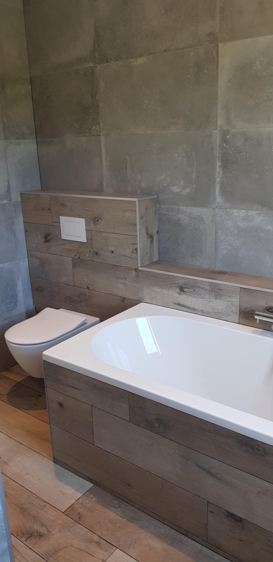 Badkamer met houtlook-tegels en ligbad